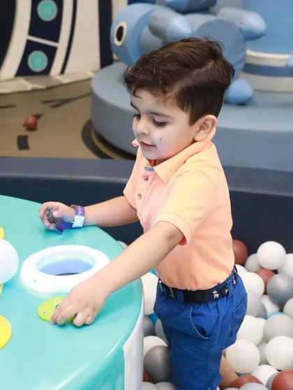 A young boy completely focused on one of our interactive consoles in the ball pit area. These games add a modern twist to classic play.