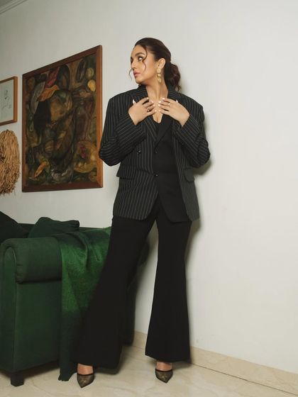 A standing portrait from the same session, showcasing the full power-suit ensemble in a chic, home-like setting.