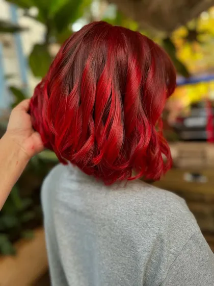 This fiery red is not for the faint of heart. We went for a full global color and a sharp bob cut for a complete makeover that is pure confidence. This look required bleach to get that vibrant, true red.