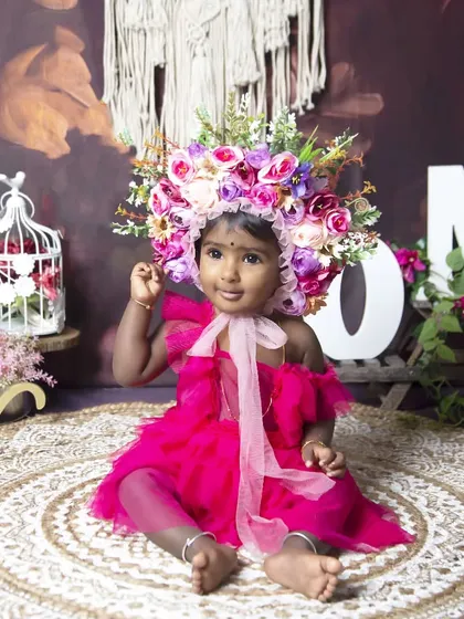 A beautiful first birthday portrait in a floral wonderland. The oversized flower crown and 'ONE' sign make this a truly special way to mark the occasion.