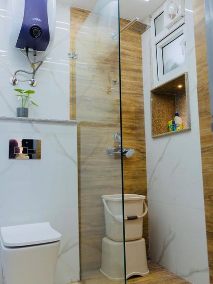 This bathroom features light-colored tiles with a wood-grain pattern accent wall in the shower, creating a warm and natural feel.