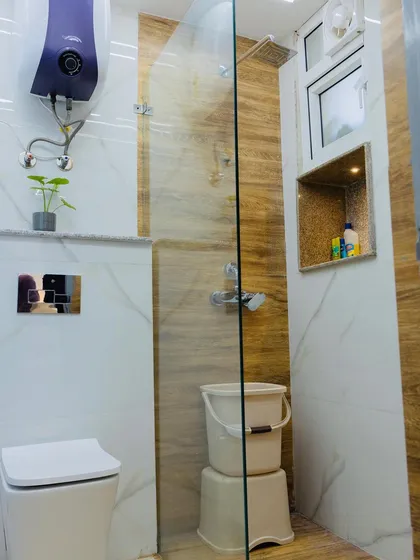 This bathroom features light-colored tiles with a wood-grain pattern accent wall in the shower, creating a warm and natural feel.