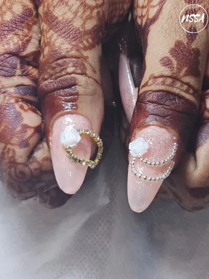 This beautiful bridal set was created by one of our students. They learn to design nails that complement traditional attire and henna, using 3D flowers and delicate chain accents.