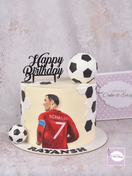 A full view of the hand-painted Ronaldo cake, showing the clean buttercream finish and edible soccer ball decorations. This is a great option for a sleek, modern take on a sports theme.