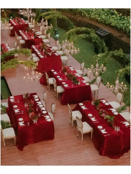 An aerial view of the red-themed engagement dinner, showing the beautiful layout of the tables amidst lush greenery and elegant lighting.