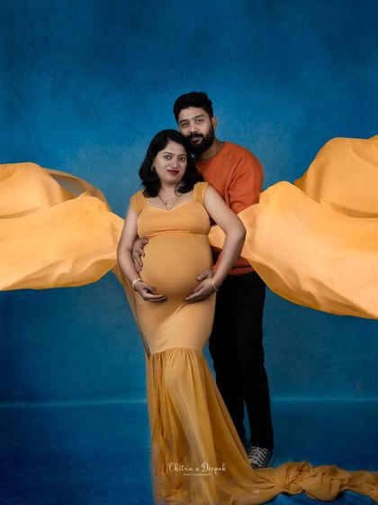 A powerful and artistic couple's portrait. The flowing yellow fabric creates a stunning visual effect against the blue background.