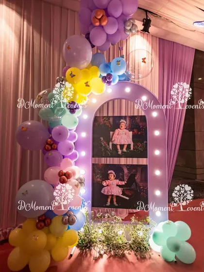A charming photo display for a princess party. A lighted arch frames two large photos of the birthday girl, surrounded by a colorful assortment of pastel balloons and flower details.