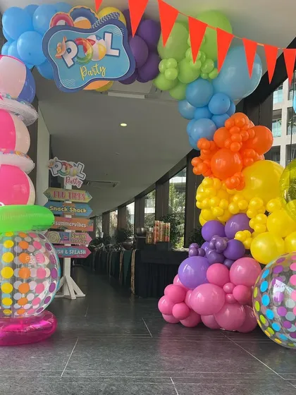 A colorful balloon arch and inflatable decorations creating a festive entrance for a fun and splashy pool party.