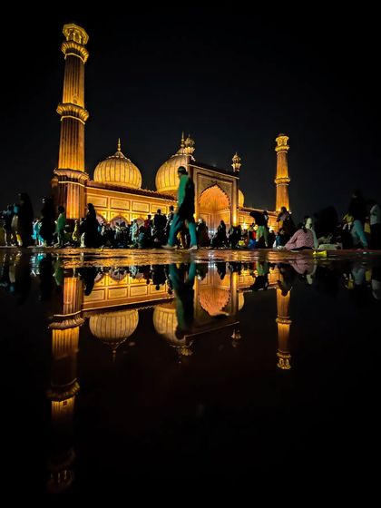 The magnificent Jama Masjid in Delhi, perfectly reflected in a puddle after rain. This night shot captures the grandeur of Mughal architecture with a creative, symmetrical composition.