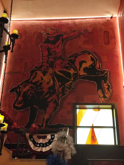 The finished bull rider mural, a powerful centerpiece for the cafe's interior. The warm red and orange tones create a desert vibe that fills the entire space.