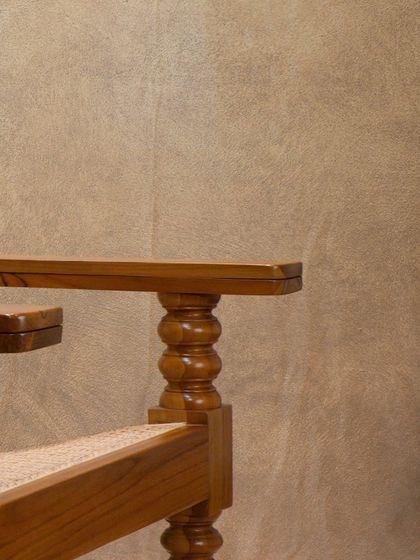 The armrest and turned leg detail of the 'Orca' lounge chair, showcasing the solid construction and decorative carving that defines this piece.