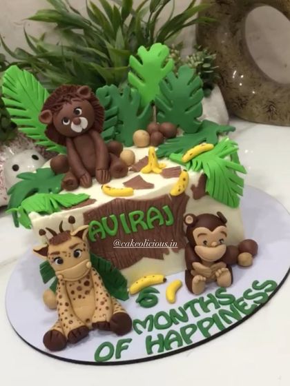 This view shows the personalized name "Aviraj" on the safari-style cake.