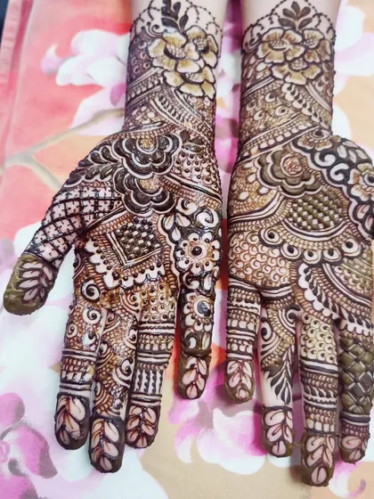The palms are decorated with a dense network of traditional motifs, including paisleys, dots, and fine lines.