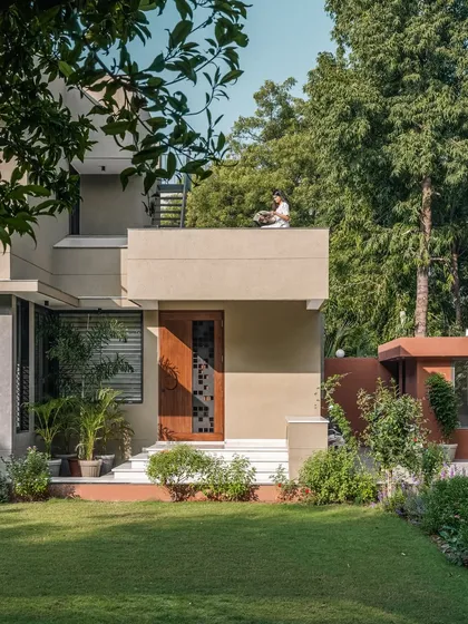 **The Glow House, Ahmedabad:** The exterior of this home is designed to capture the magic of light throughout the day. Tucked into a lush garden, the structure's clean lines and deep porch create a perfect spot for quiet moments, where the architecture itself becomes a frame for the surrounding nature.
