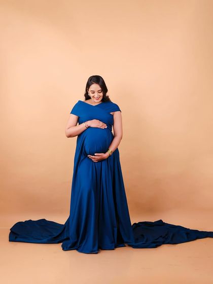A simple and serene portrait in a beautiful blue gown. The fabric pools at her feet, and her gentle hold on her bump creates a timeless and peaceful image.