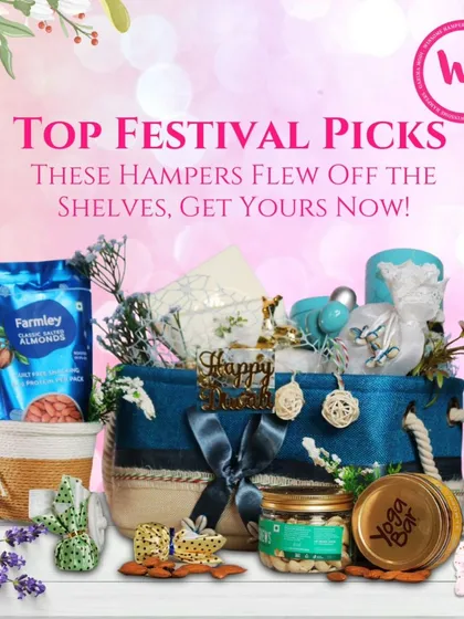 One of my top-selling festival hampers, presented in a stylish blue and jute basket. It's filled with Farmley almonds, a Yoga Bar, scented candles, and other curated items, showing a popular combination of healthy and festive products.