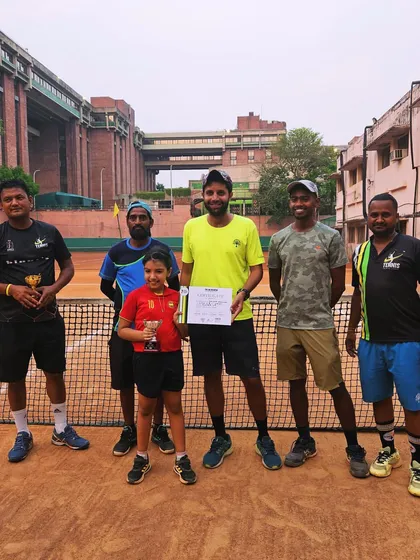 A young girl proudly holding her trophy, flanked by our coaching staff.