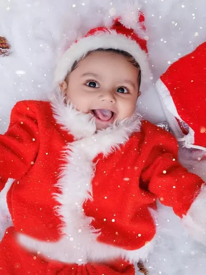 A happy baby Santa lies in a bed of snow, surrounded by presents. This is pure holiday cheer!