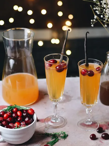 A festive cranberry and vanilla cocktail, perfect for the holidays. The bokeh from Christmas lights in the background and the elegant glassware create a celebratory mood.