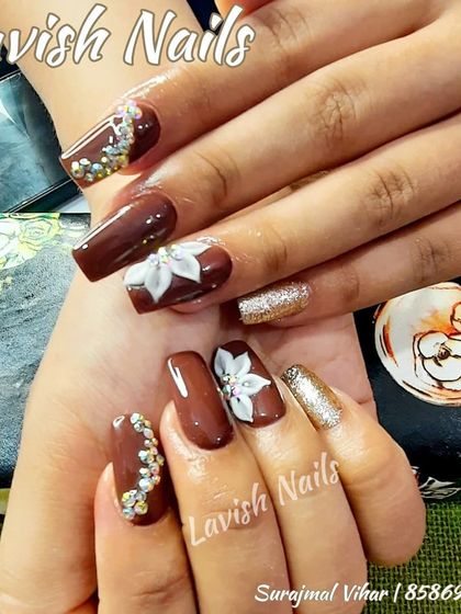A luxurious nail set in deep brown, accented with gold glitter and 3D white flowers with rhinestone centers.