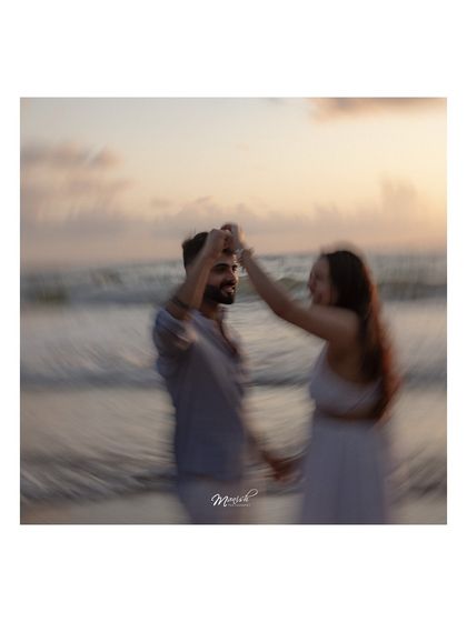 An artistic motion-blur shot of the couple dancing on the beach at sunset, creating a dreamy and romantic effect.