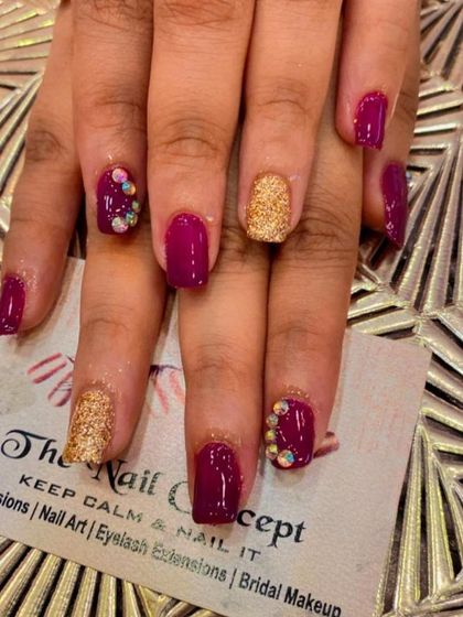 A rich and royal look with square-shaped nails. This set features a deep magenta polish, gold glitter accent nails, and accent nails with clusters of iridescent crystals.