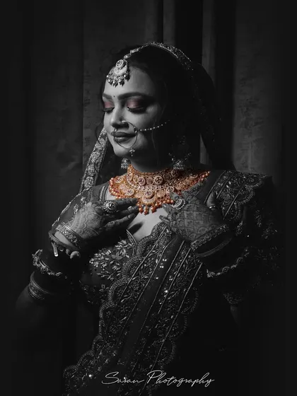 A stunning black and white bridal portrait with selective coloring on her gold jewelry, creating a striking contrast.