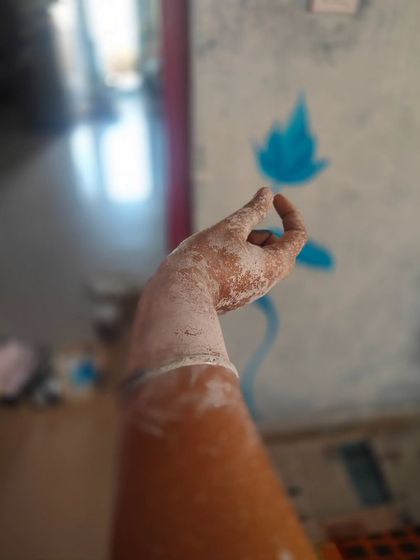 The very beginning of a new mural. My paint-splattered arm against a wall with the first few strokes of blue shows the raw, physical start of any project. It’s a moment of pure potential before the final image takes shape.