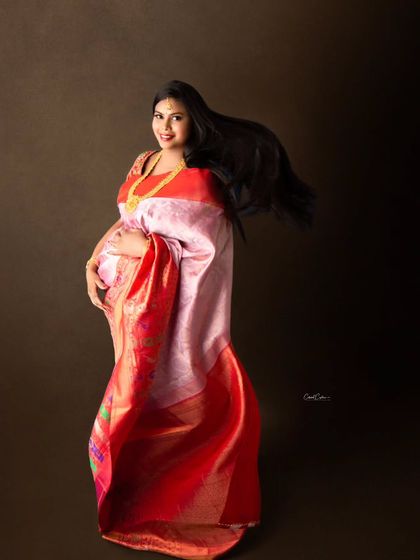 A joyful, dynamic shot with the mom-to-be's hair and saree fabric caught in motion, creating a feeling of celebration.