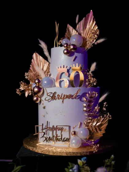 The 60th birthday cake under the party lights. The purple lighting gives the white and gold design a completely different, magical look.