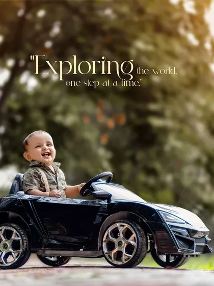 Exploring the world one step at a time. This smiling boy is clearly enjoying his ride in a cool black toy car.