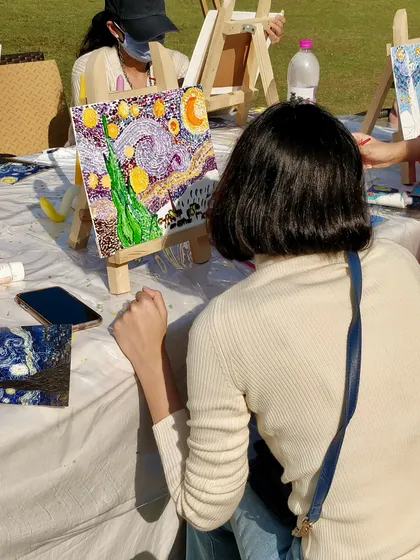A participant admires her nearly finished pointillist-style 'Starry Night' painting.