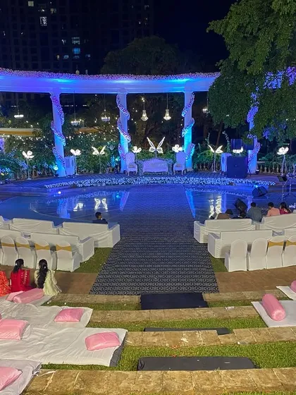 We design the entire event space to be cohesive. This wide shot shows the amphitheater reception setup, including the tiered floor seating with cushions for a relaxed viewing experience, all focused on the beautifully lit stage.