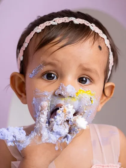 A close up of the messy face that says it all. The vibrant colors of the cake and her sweet expression make this a perfect cake smash portrait.
