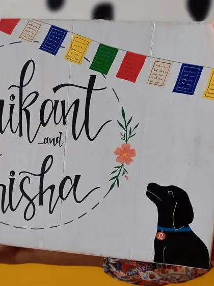 A duplicate of 73, a close-up on the hand-painted details of the "Srikant and Trisha" name board, showing the delicate flower and the silhouette of their dog.