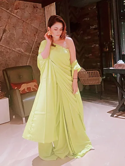 The one-shoulder cut and draped silhouette of this neon outfit offer a modern alternative to a traditional saree. It’s a great example of how we can play with contemporary ethnic wear for parties.