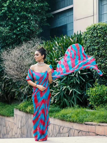Capturing a colorful saree in motion against a green, natural backdrop. The flowing pallu creates a sense of dynamism and freedom, highlighting the lightweight fabric.
