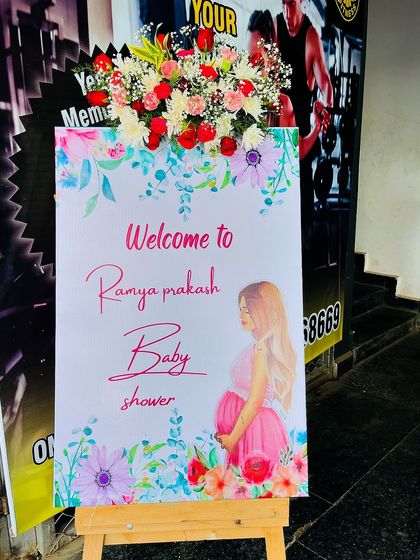 A custom welcome board for a baby shower, decorated with a beautiful arrangement of fresh flowers. This is a perfect way to greet guests and set a festive tone.