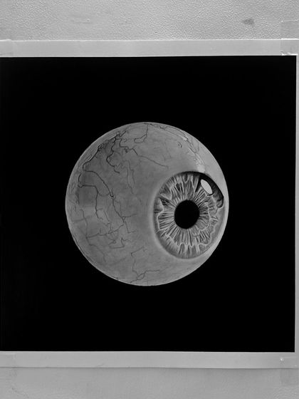 The "Eyeball" drawing on the wall. The stark black background makes the eyeball feel like it's floating in space.