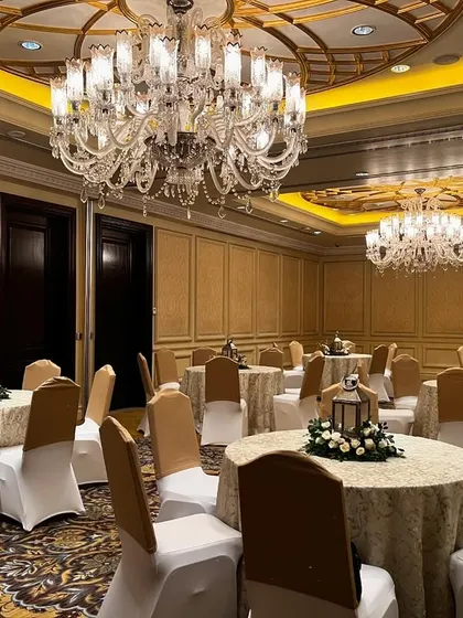 The elegant ballroom at The Leela Palace, Delhi, set up for a luxury event. The classic decor and grand chandeliers provide a perfect canvas for a royal celebration.