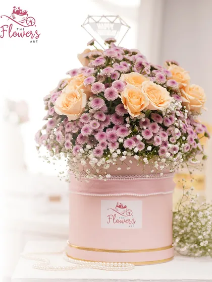 Celebrate a special day with a birthday-themed flower box. This arrangement combines soft peach roses and pink daisies, topped with a sparkling 'Happy Birthday' sign for a festive and personal touch.