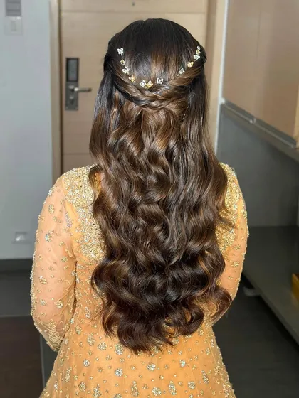 Beyond makeup, I am a passionate hairstylist. This half-up hairstyle with soft, cascading waves and delicate butterfly accessories creates a romantic and whimsical look, perfect for an engagement or sangeet.