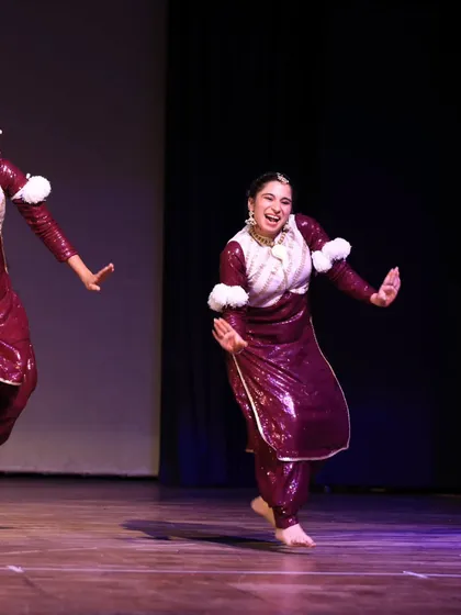 Two performers from the Bhangra Queens share a moment of fun and connection during their energetic folk routine.