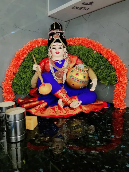 A simple yet beautiful decoration for a goddess idol, with a garland arch made of green leaves and orange flowers.