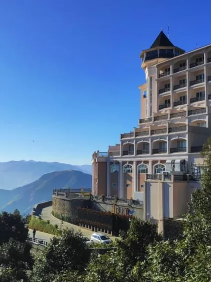 A clear day view of the ITC Tavleen resort in Chail, showcasing its commanding position in the Himalayan landscape. The building's tiered structure ensures that many rooms and balconies offer panoramic views.