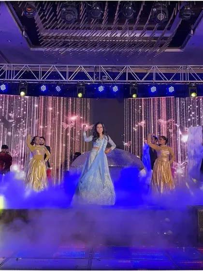 The bride stands out in her beautiful blue lehenga, surrounded by dancers in gold and a magical smoke effect.