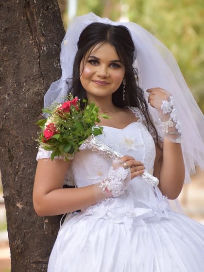 The bride is holding her bouquet, her hair and veil perfectly in place. This is a timeless look for a Catholic wedding ceremony.