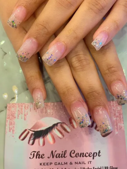 Clear nail extensions in a square shape with a beautiful silver and blue glitter gradient starting from the tips. This creates a lovely, icy effect that is both simple and eye-catching.