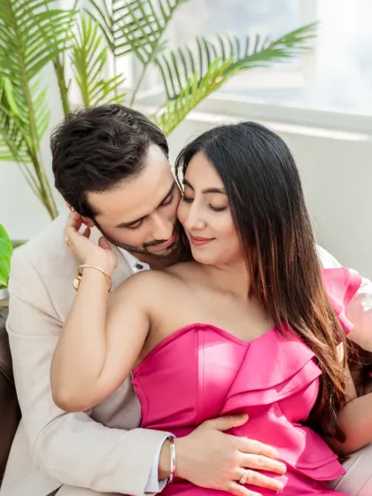 An intimate and tender close-up of the couple on a sofa. The soft lighting and their gentle embrace highlight their deep affection.