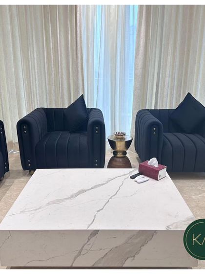 This shot highlights the two matching armchairs from the navy blue tufted set. The vertical tufting and studded details on the arms showcase our attention to fine detailing in every piece.